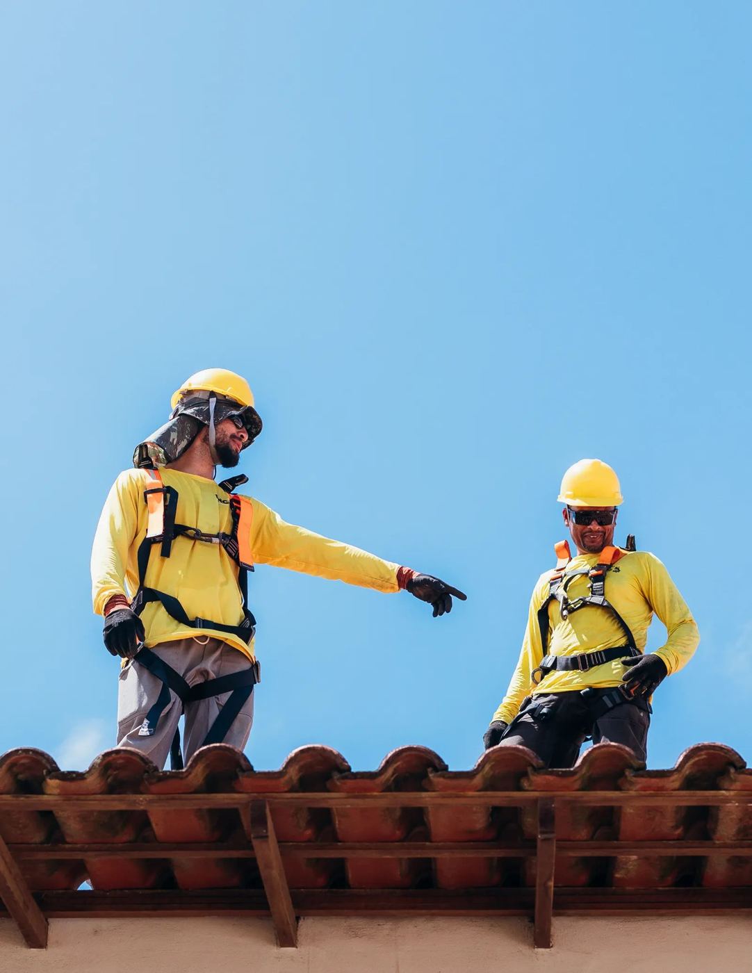 Roofers in safety gear working on a tile roof